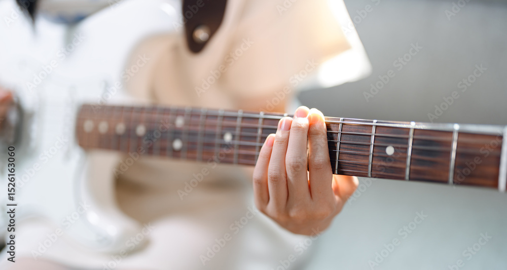 Fototapeta premium Focus hand of woman on playing electric guitar chord music