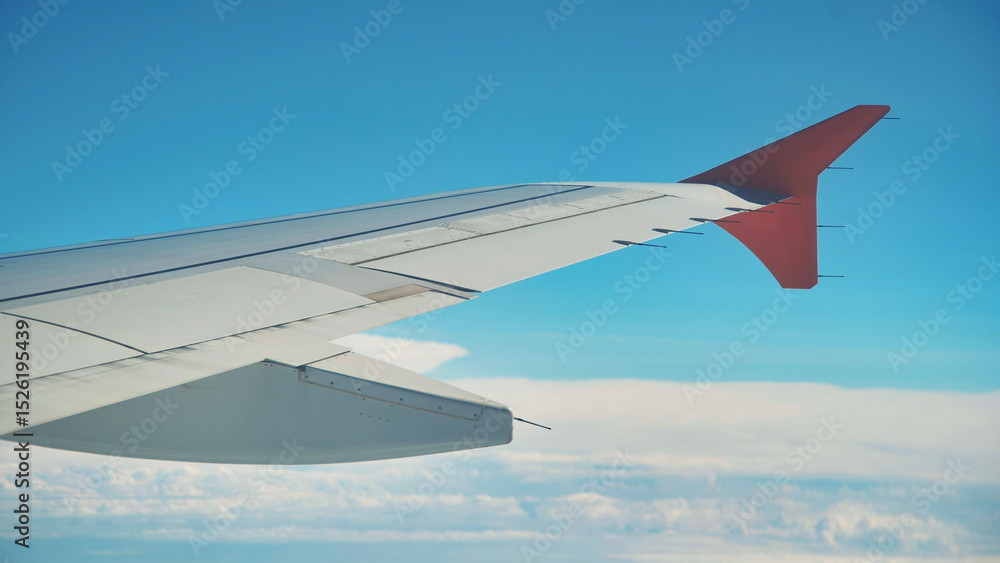 Obraz premium Airplane wing flying above the clouds on a beautiful sunny day