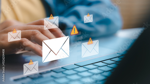 Hands typing on a laptop with warning email icons, representing phishing attacks, scam messages, and email security threats in a digital communication concept.