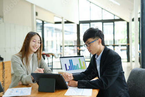 Two business people discuss financial strategy and collaborate with colleagues.