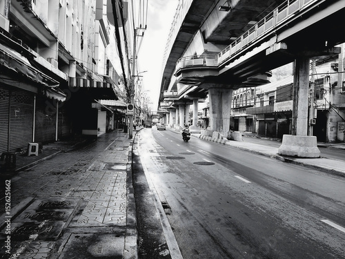 Fast devlopment in the big city and empty road in the morning. Thai, Thailand, Bangkok, gray, grey, big city, electric line, real estate, pavement, sidewalk, footpath, vintage, economy, residential .