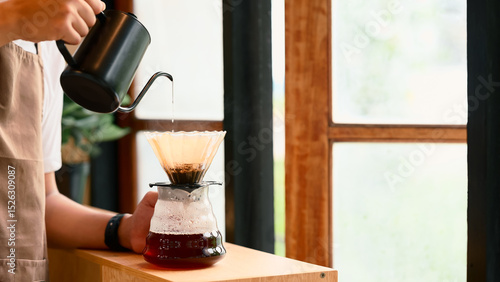 Man pouring hot water into a coffee dripper using a gooseneck kettle