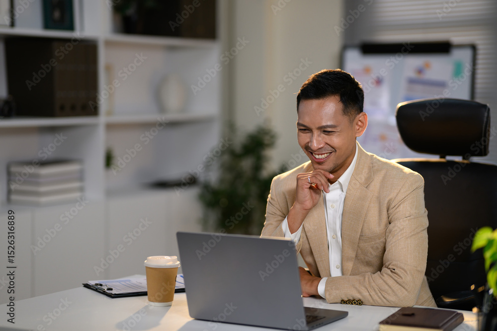 Confident businessman in a beige suit smiling, attending an online meeting at his desk Confident businessman in a beige suit smiling, attending an online meeting at his desk