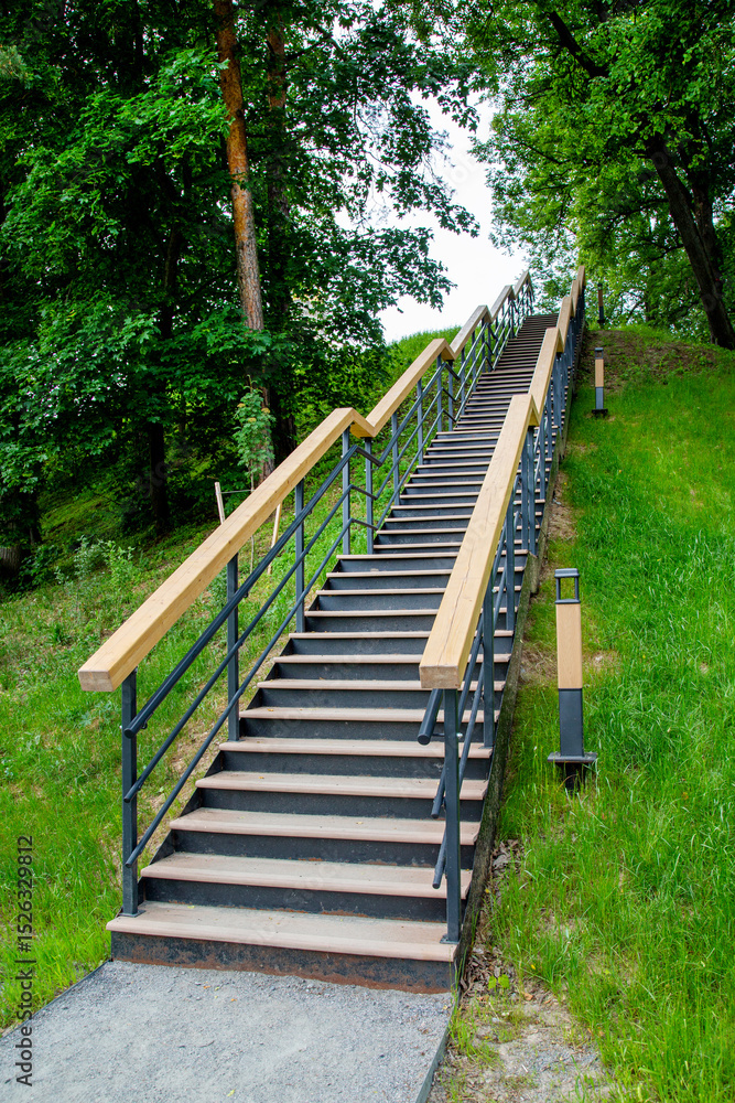 Obraz premium A metal staircase with a handrail in a park among green trees. Architecture of World tourism.