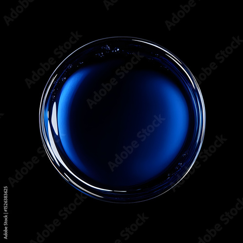 A top-down shot of a blue liquid in a clear glass bowl against a black background.