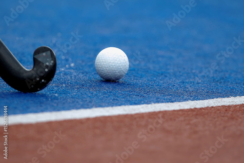 Hockey ball and hockey stick passing through wet playing field lines