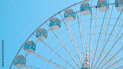 Close view of Ferris wheel cabins on sunny sky background in park setting