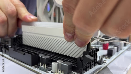 Hands disassemble the device with the motherboard in the electronics repair laboratory using tools and components for troubleshooting and maintenance. High quality 4k footage