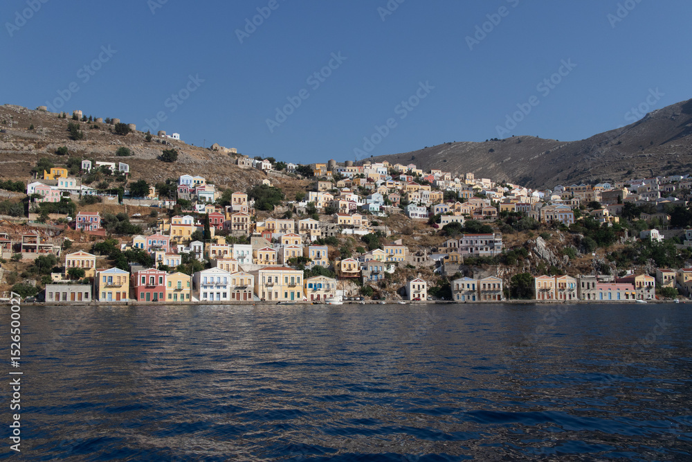 Fototapeta premium Case colorate sulla costa dell’isola con mare calmo e cielo azzurro..