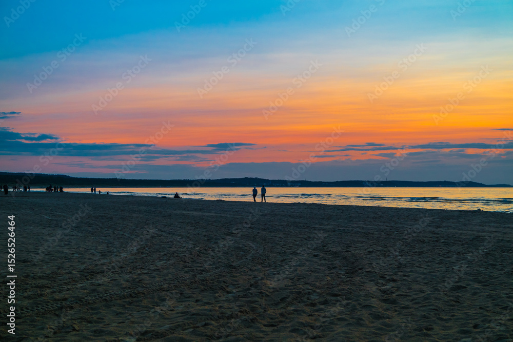 Fototapeta premium Swinemünde -Polen. Ein Strand bei Sonnenuntergang und Farben Reflektionen im Meer