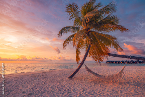 Fototapeta Naklejka Na Ścianę i Meble -  Closeup sunset view palm tree with hammock swing over golden sand sea. Romantic inspire carefree tropical landscape with vivid sky, perfect for summer vacation, relaxation, and dreamy beach background