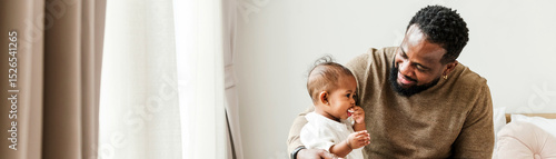 Canvas Print Loving father spending quality time with his baby daughter at home, symbolizing authentic family diversity and Father’s Day bonding