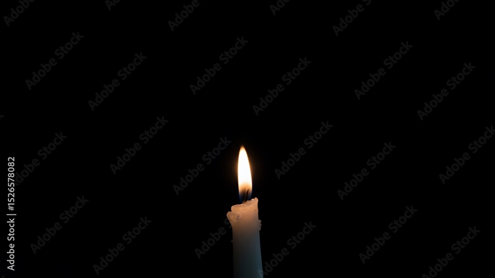 Fototapeta premium A single candle burning against a deep black background offering warmth and light