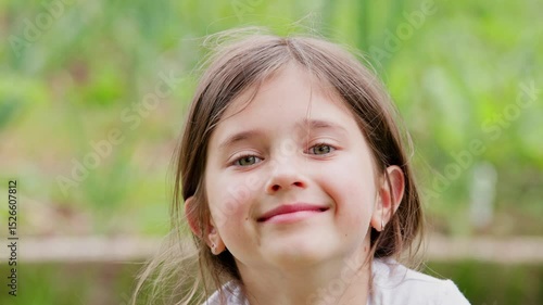 Little beautiful girl smiling looking at camera outdoors. Cute kid smile at camera