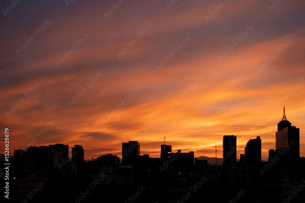 Silhouetted skyline at vivid sunset, Colonia del Valle, Mexico City, horizontal framing emphasizing urban profile and intense orange light in the sky Silhouetted skyline at vivid sunset, Colonia del Valle, Mexico City, horizontal framing emphasizing urban profile and intense orange light in the sky