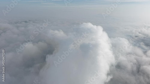 A stunning aerial view captures the serene beauty of clouds from above. Soft, billowing formations stretch across the sky, bathed in golden sunlight.