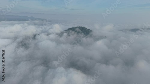 A stunning aerial view capture the serene beauty of clouds from above. Soft, billowing formations stretch across the sky, bathed in golden sunlight and casting gentle shadows over the landscape below.