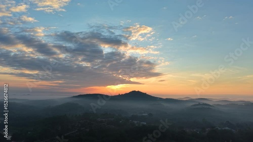 Dramatic morning sunrise over an Asian oil palm plantation. Golden light pierces through low mist, casting long shadows across neat rows of palm trees and creating a warm, cinematic landscape.