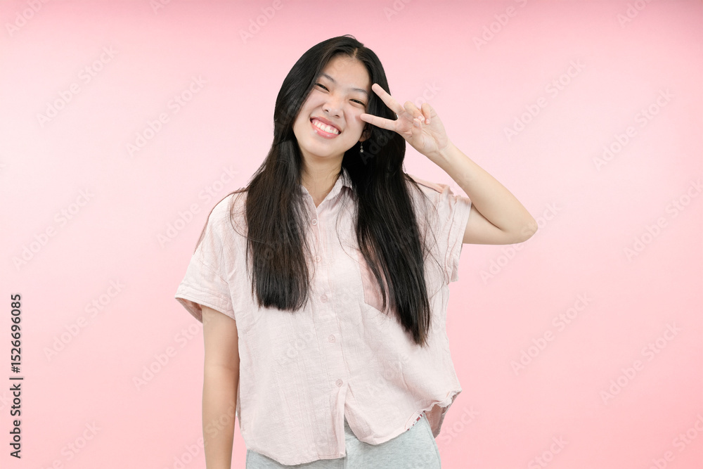 young asian woman making peace gesture in studio pink background young asian woman making peace gesture in studio pink background