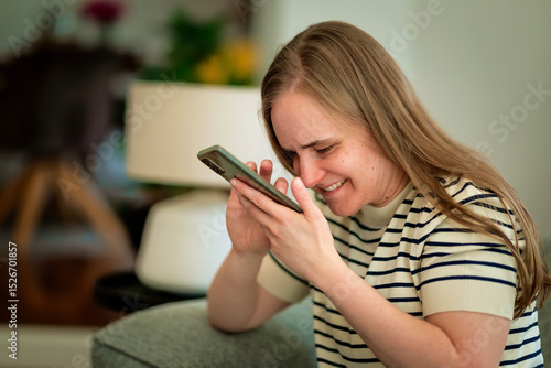 Tableau sur toile A visually impaired woman sitting on the sofa and using her cell phone