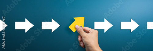 Group of arrows in one direction and businessman hand holding arrow pointing in the different way. Business concept for new ideas creativity and innovative solution