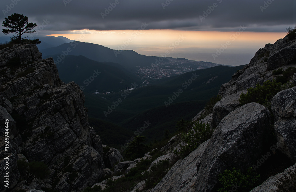 Naklejka premium Moody mountainous landscape with lone tree, rocky foreground, sunset.