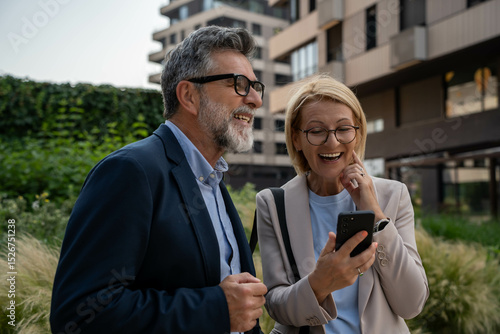 Smiling Businessman and Businesswoman Using Smartphone outdoor, Happy and Positive at Work