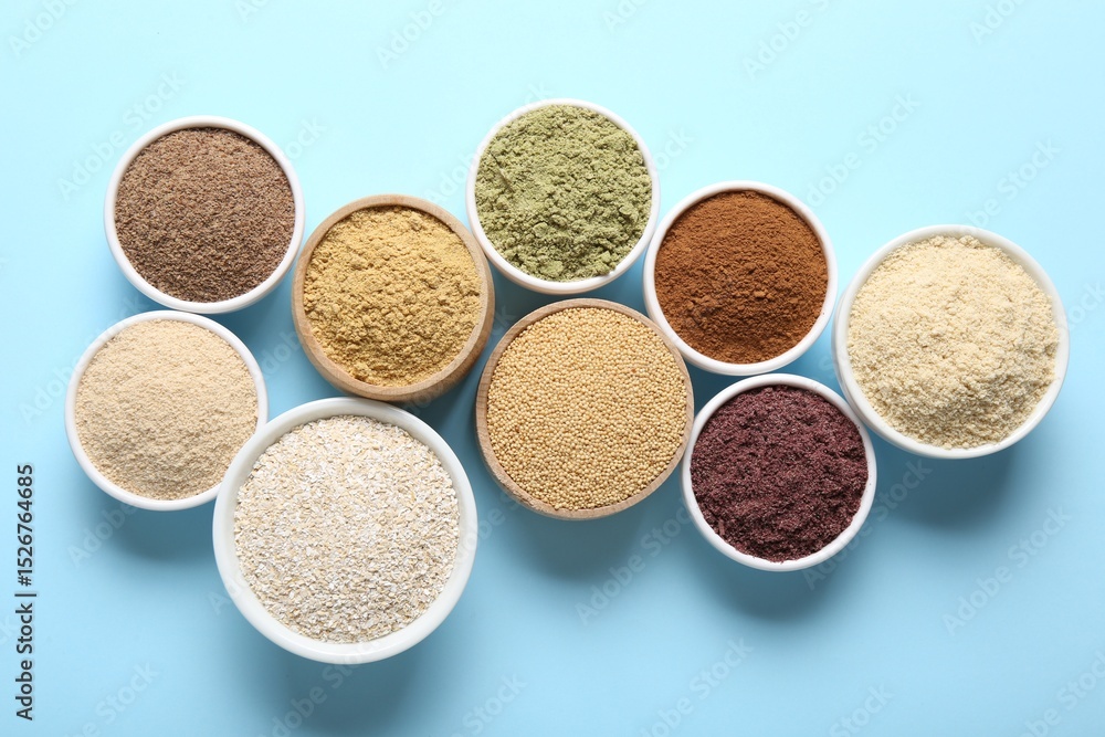 Different superfood powders in bowls on light blue background, flat lay Different superfood powders in bowls on light blue background, flat lay