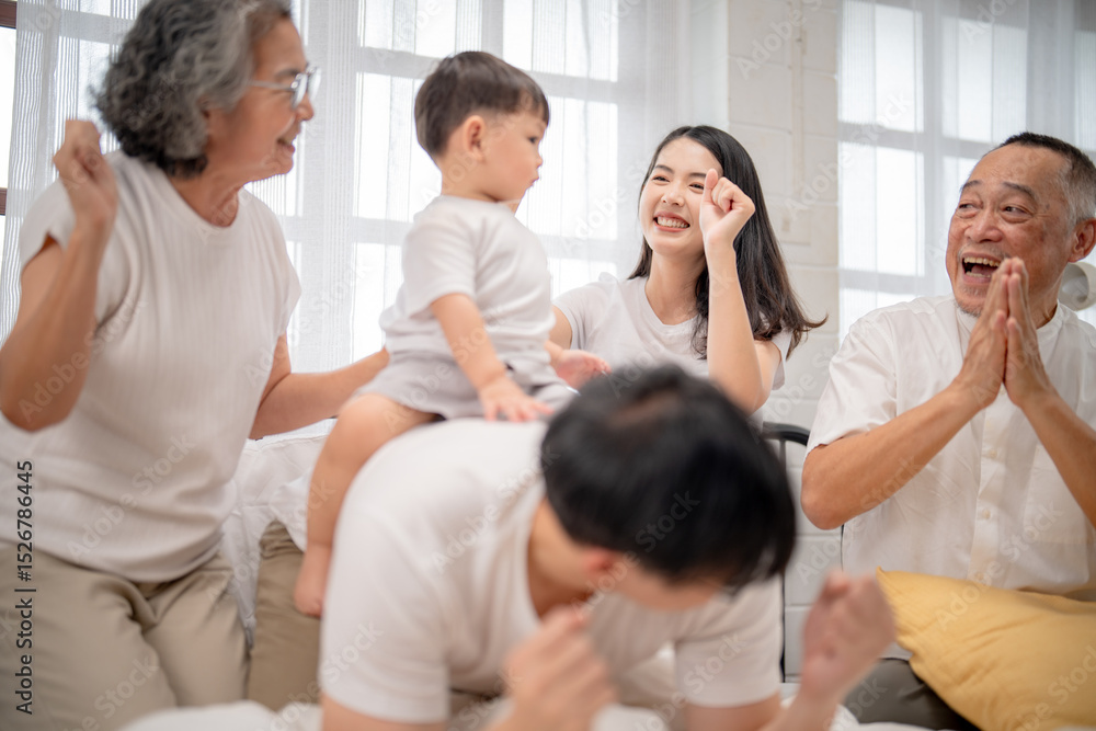 Obraz premium Joyful family gathering at home with grandparents, parents, and child sharing laughter and playful moments in the morning light