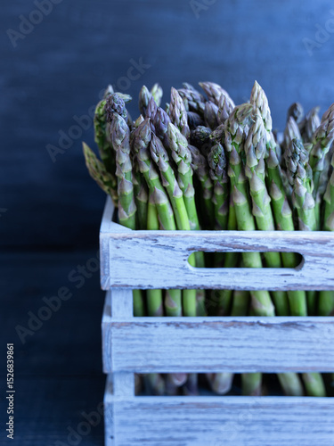 Green Asparagus in Wooden Crate. Harvested green asparagus neatly arranged in a weathered gray crate, ideal for market or farm visuals