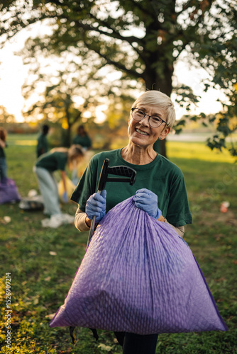 Cuadro en lienzo Senior volunteer holding trash bag and grabber for litter pickup in park