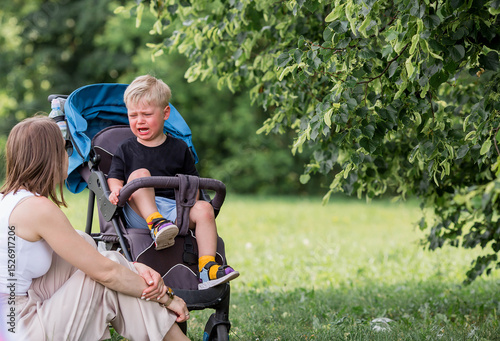 A little boy in a stroller and his mom. Childish hysteria. The child screams, cries, gets cranky and gets hysterical. Discontent.