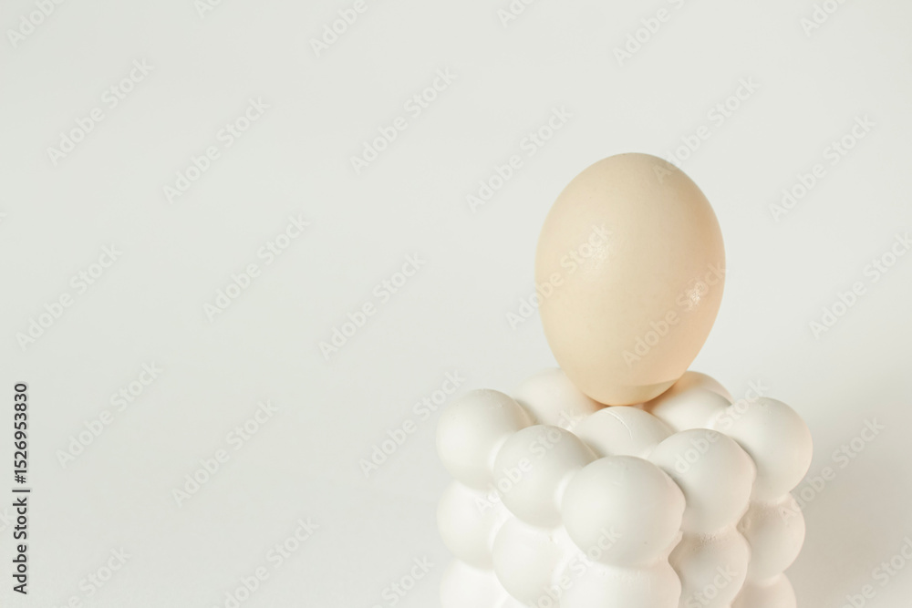 White egg placed on a modern bubble-style egg holder on isolated white background. White egg placed on a modern bubble-style egg holder on isolated white background.