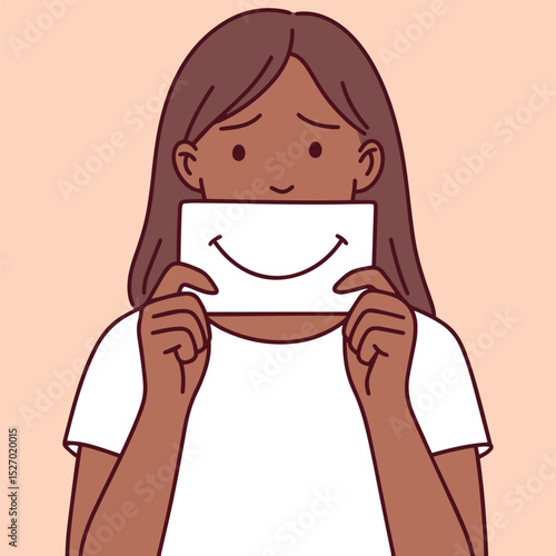 Dark black brown skinned girl holds a paper smile in front of her mouth. True expression hidden, representing faked emotions and inner sadness