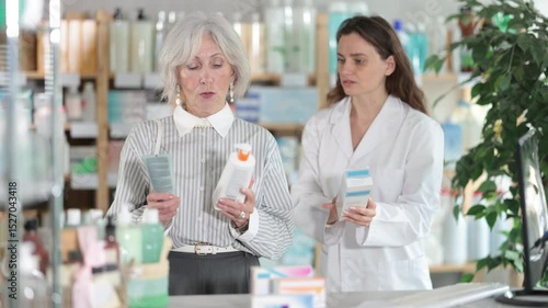 Wallpaper Mural Mature woman choose cream, buys product in drug store. Checking for absence of GMOs, age restrictions and recommendations for use. Woman pharmacist offers product, promotes product of European brand Torontodigital.ca