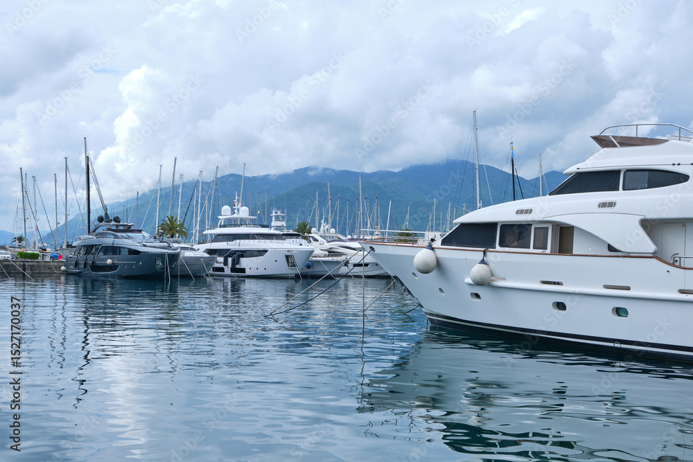 Fototapeta premium Luxury yachts docked at marina in Porto Montenegro with mountains and cloudy sky in the background