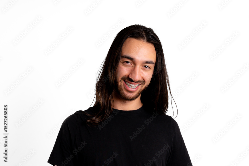 Fototapeta premium Young adult man, Latino, with braces, smiles looking at the camera against white background
