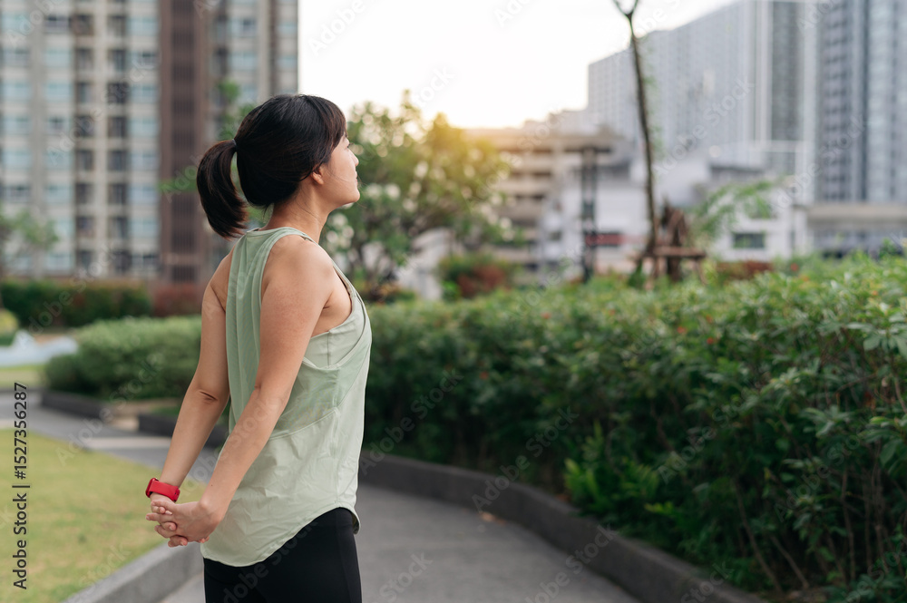 Fototapeta premium Asian woman fitness yoga workout. stretching exercise reduces shoulder pain muscle strain inflammation injury risk for medical wellness and healthcare in an urban city at sunset