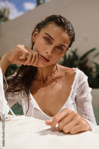 Close-up portrait of a woman with wet hair and natural makeup, her skin glowing in soft light. A moment of quiet elegance and femininity.
