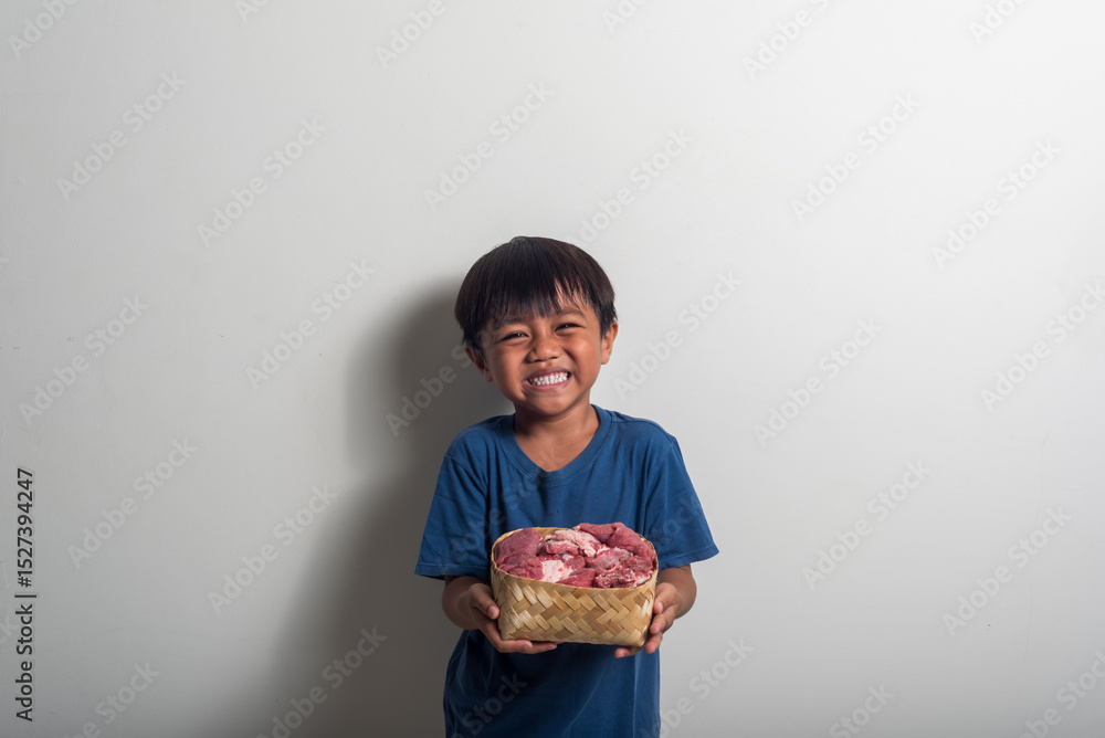 Smiling Boy Holds Basket of Raw Meat Against White Wall Smiling Boy Holds Basket of Raw Meat Against White Wall