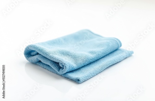 Blue folded microfiber cleaning cloth lies on white reflective surface. Soft texture wipe dust, dirt. Clean screen glasses lens. Cleaning supplies for household. Gentle wipe tech equipment.