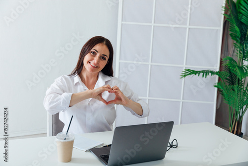 Business woman showing her hands heart at desk in office