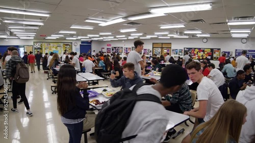 High school students engage in lunch activities in bustling cafeteria during midday
