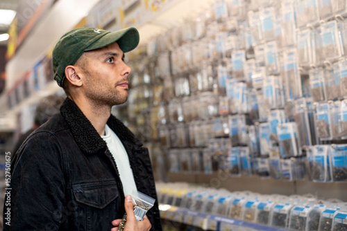Fotografi Young man selecting screws for his home project in a hardware store