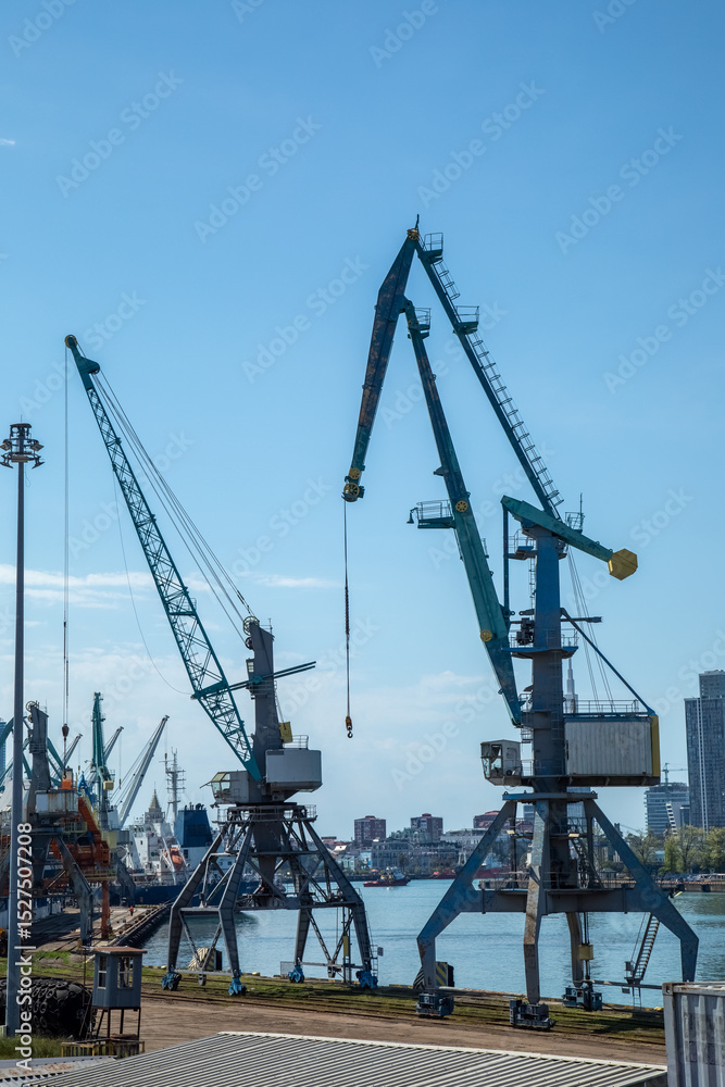 Industrial port cranes and cargo terminal with city skyline background Industrial port cranes and cargo terminal with city skyline background