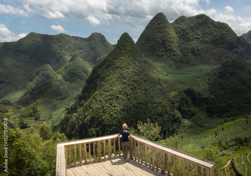 Tableau sur toile Solo female traveler at the viewpoint overlooking forested hills of Dong Van kar