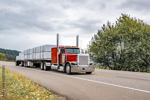 Canvas Print Red classic big rig semi truck with chrome exhaust pipes transporting covered fa