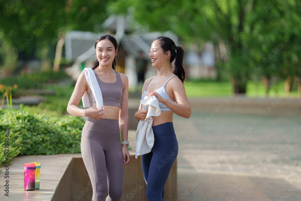 Naklejka premium Two young women walking and talking after exercising in park