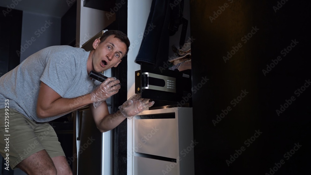 Thief opens hotel safe box lighting up face with excitement Thief opens hotel safe box lighting up face with excitement