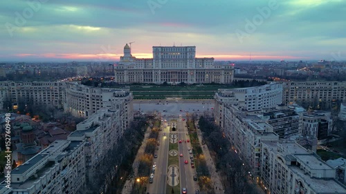 Aerial drone footage of the house of the people in Bucharest. High angle golden hour shot of the  Parliament building in the capital or Romania. Massive governmental structure seen from the air.
